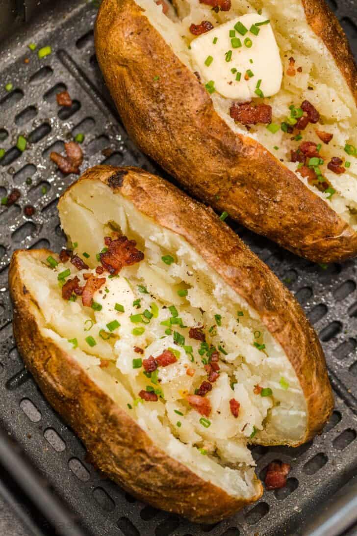 Easy and fail-proof recipe for Air Fryer Baked Potatoes. Potatoes in the air fryer have crisp salty skin and a soft and fluffy center. Air fryer baked potatoes topped with butter, bacon, and chopped greens.