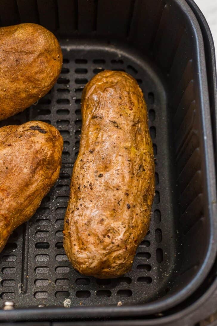 A delicious and SIMPLE air fryer baked potato recipe that gives you the ultimate crispy yet soft baked potato. Cooked baked potato in the air fryer basket topped with salt.