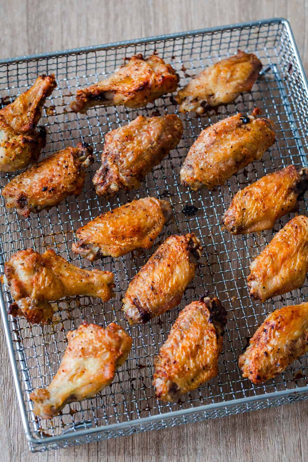 Air Fryer Chicken with crisp salty skin, perfectly seasoned with garlic and lemon pepper. Air fried chicken wings cook so fast with no marinating! #airfryer #airfryerchicken #airfryerchickenwings #chickenwings #crispchickenwings #chicken #airfryerrecipes #natashaskitchen chicken wings on air fryer basket