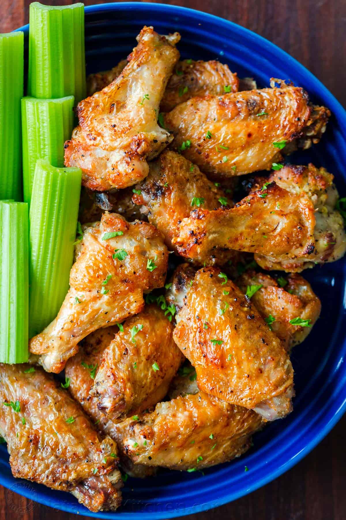 Air Fryer Chicken Wings with crisp salty skin, perfectly seasoned with garlic and lemon pepper. Air fried chicken wings cook so fast with no marinating! #airfryer #airfryerchicken #airfryerchickenwings #chickenwings #crispchickenwings #chicken #airfryerrecipes #natashaskitchen Air Fryer Chicken Wings in bowl with celery