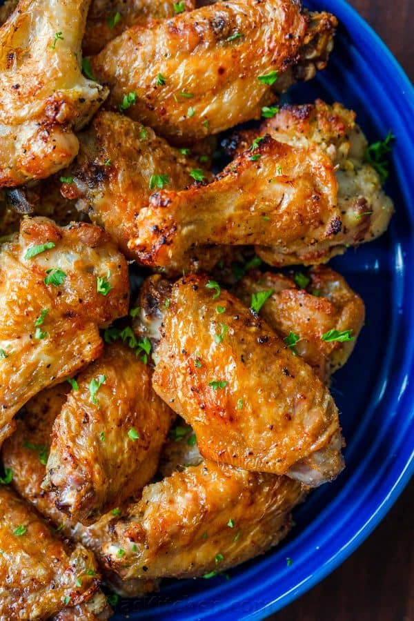 Air Fryer Chicken Wings with crisp salty skin, perfectly seasoned with garlic and lemon pepper. Air fried chicken wings cook so fast with no marinating! #airfryer #airfryerchicken #airfryerchickenwings #chickenwings #crispchickenwings #chicken #airfryerrecipes #natashaskitchen Air Fryer chicken wings garnished with parsley in blue bowl