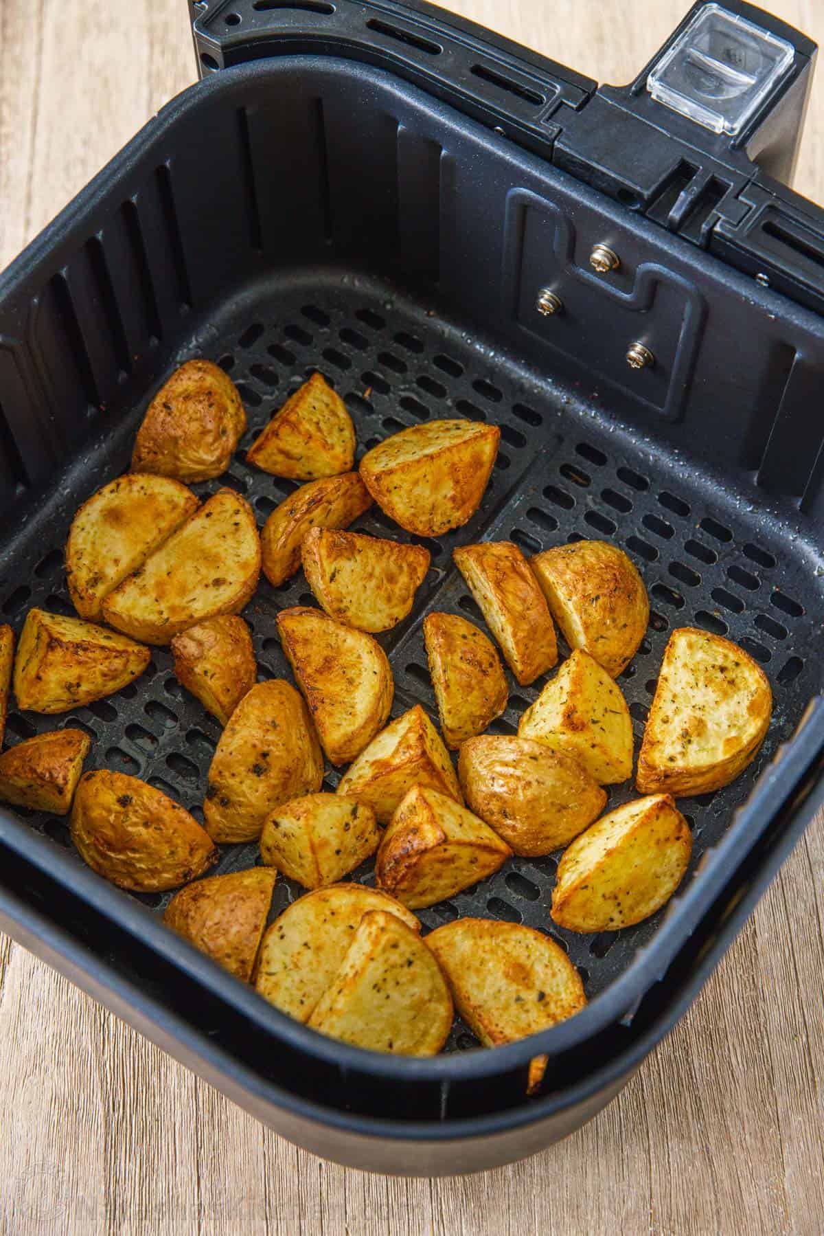 Overhead view of roasted potatoes inside the air fryer basket.