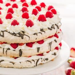Boccone Dolce has 3 crunchy meringue layers, chocolate, cream and plenty of berries. Drizzled with a berry syrup - this Boccone Dolce Cake is delicious! | natashaskitchen.com