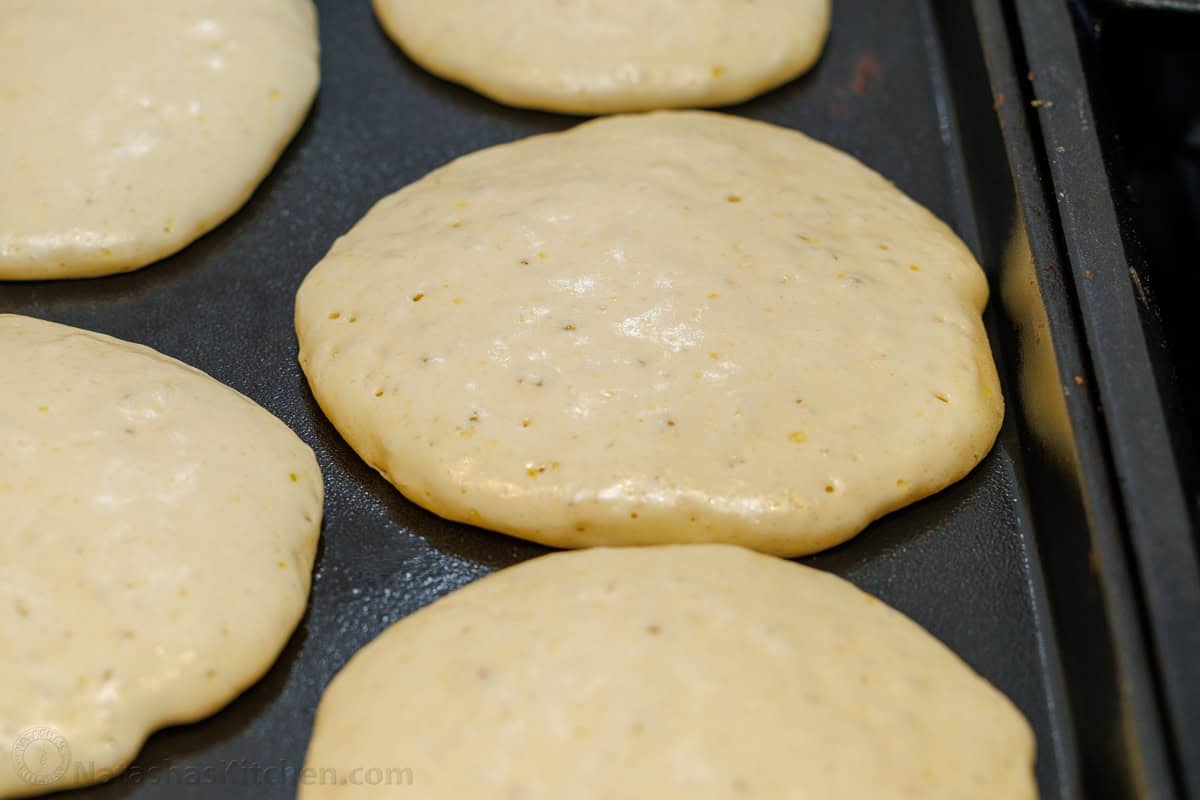 homemade pancakes ready to flip with bubbles popped on top