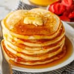 Stack of homemade buttermilk pancakes served with a drizzle of maple syrup and pat of butter