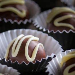 The center is a traditional Russian sponge cake called biskvit which is mixed with cooked poppy seeds and sweetened condensed milk. They are coated in melted chocolate truffles and made pretty with white chocolate.