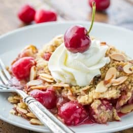 This Cherry Crumble is a family favorite! The crumbly crisp almond topping is a perfect match to those juicy plump cherries | NatashasKitchen.com