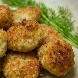 A close up of a plate with chicken and pork katleti, garnished with dill