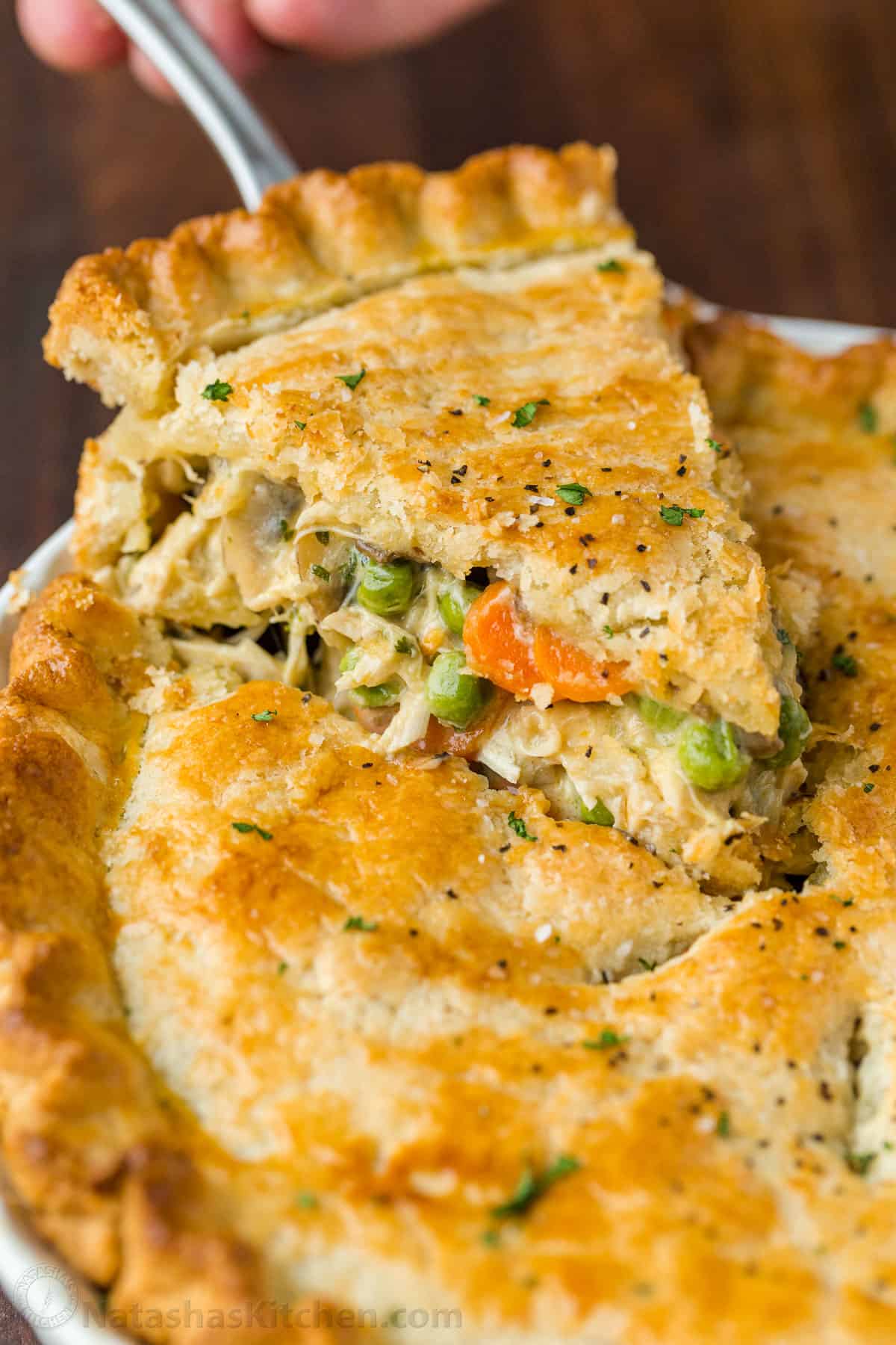 This Chicken Pot Pie has a flaky crust filled with juicy chicken and veggies in gravy. Homemade Chicken Pot Pie is the ultimate comfort food. Baked Chicken Pot pie with a slice on a pie server