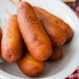 homemade corn dogs on a serving plate with ketchup and mustard