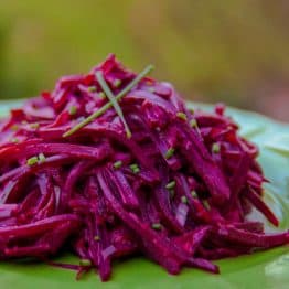 A close up of Mom's creamy beet salad on a green plate garnished with chives