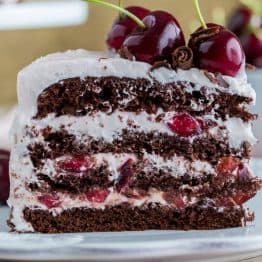 A piece of drunken cherry cake on a plate garnished with fresh cherries