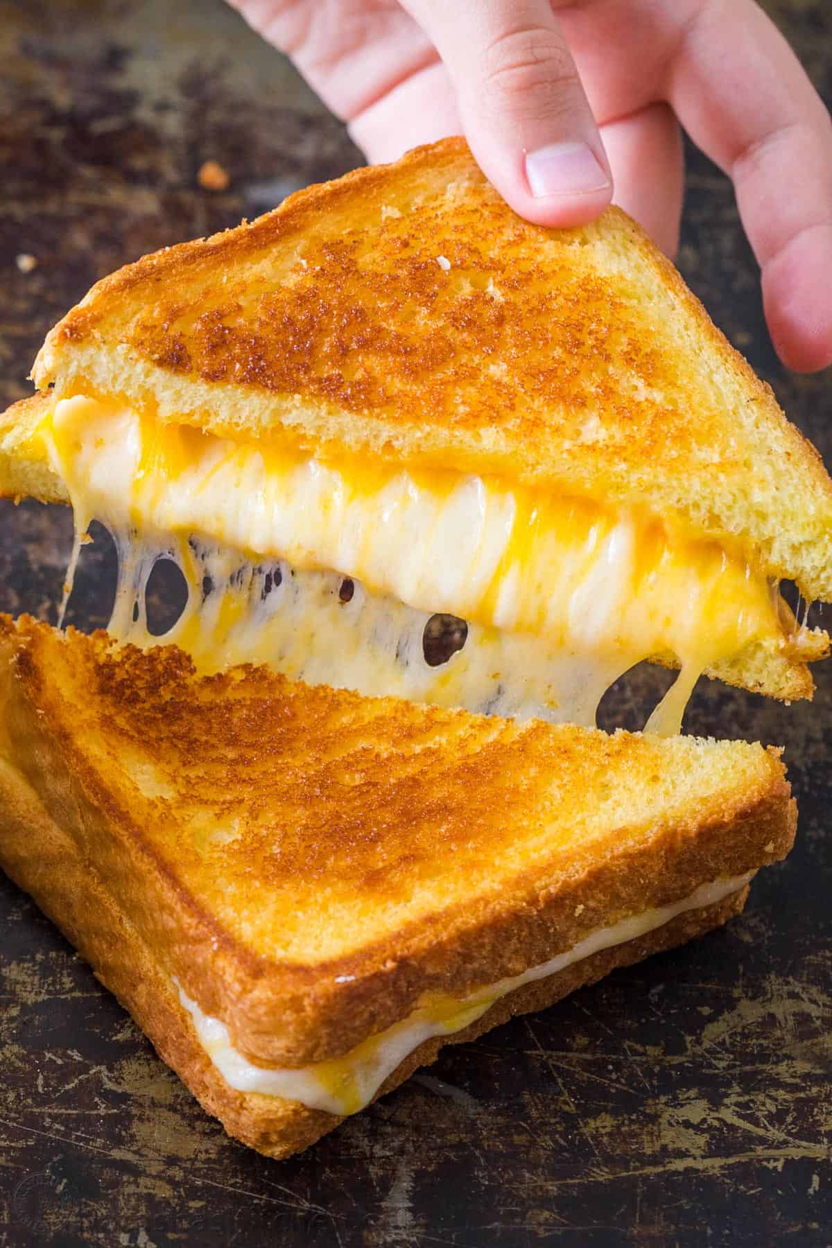 Learn how to make the best Grilled Cheese sandwich with a crisp, buttery exterior and gooey cheese center. Make grilled cheese like a pro! Grilled Cheese cut in half showing cheesy center