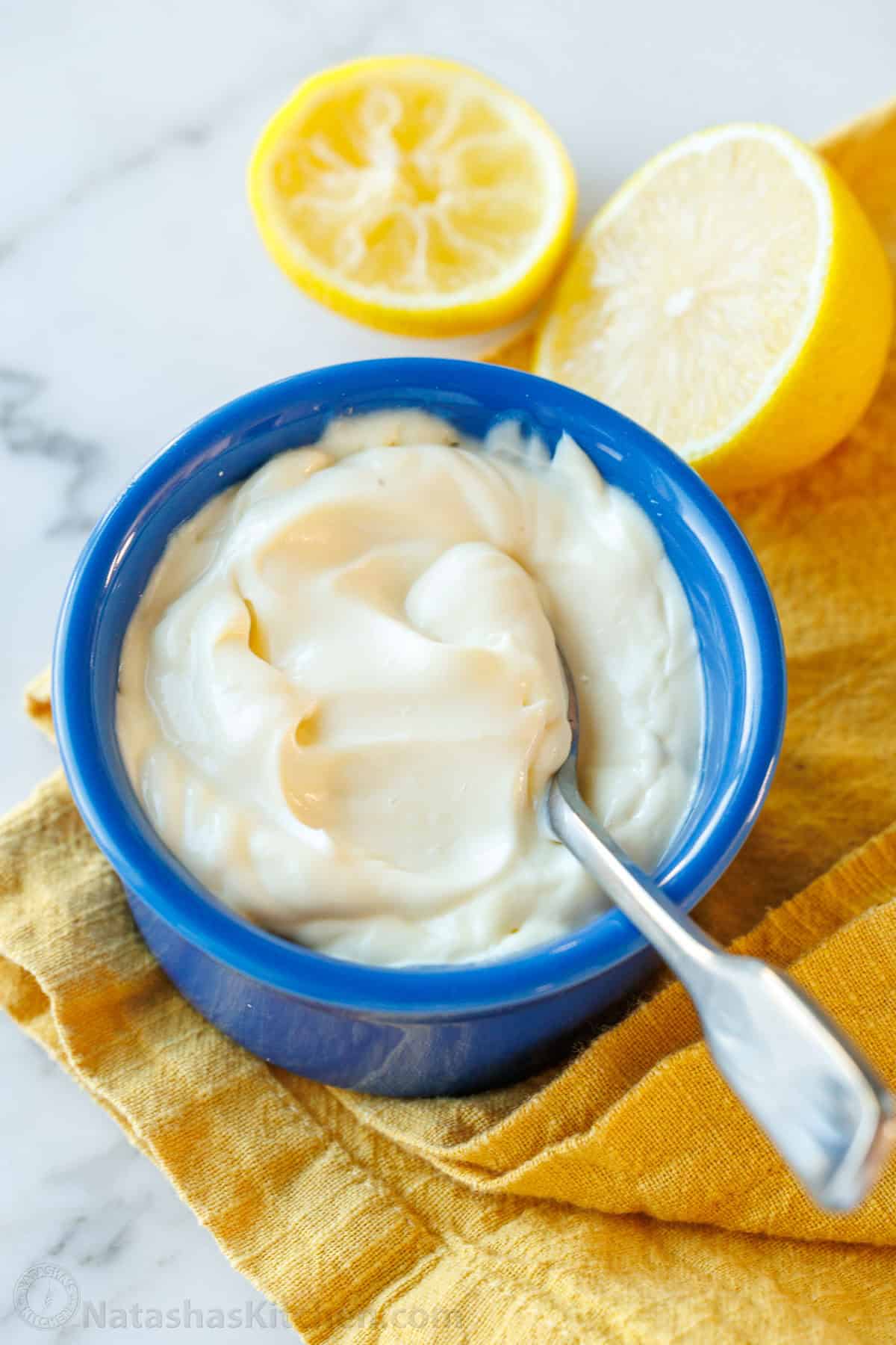 Replace store-bought mayo with your own creamy, delicious homemade mayonnaise—simple, fresh, and perfect for for everything from sandwiches to salads and more! Creamy Homemade Mayonnaise in a blue ramekin with a spoon.