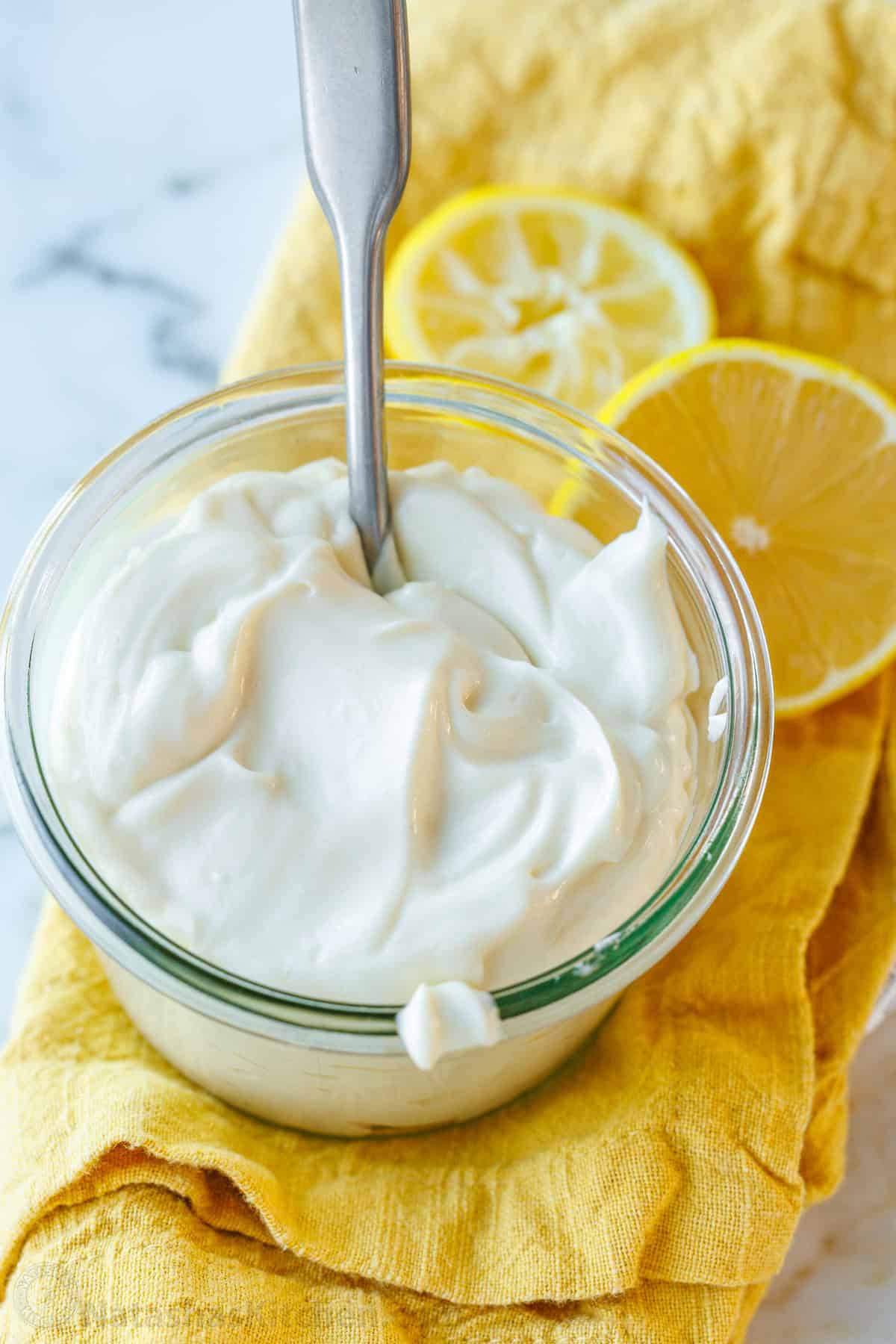 Best Homemade Mayonnaise recipe that tastes like storebought but has better ingredients. It's creamy, easy, delicious, and takes 1 minute. Homemade Mayonnaise in a glass jar with lemon wheels surrounding it.