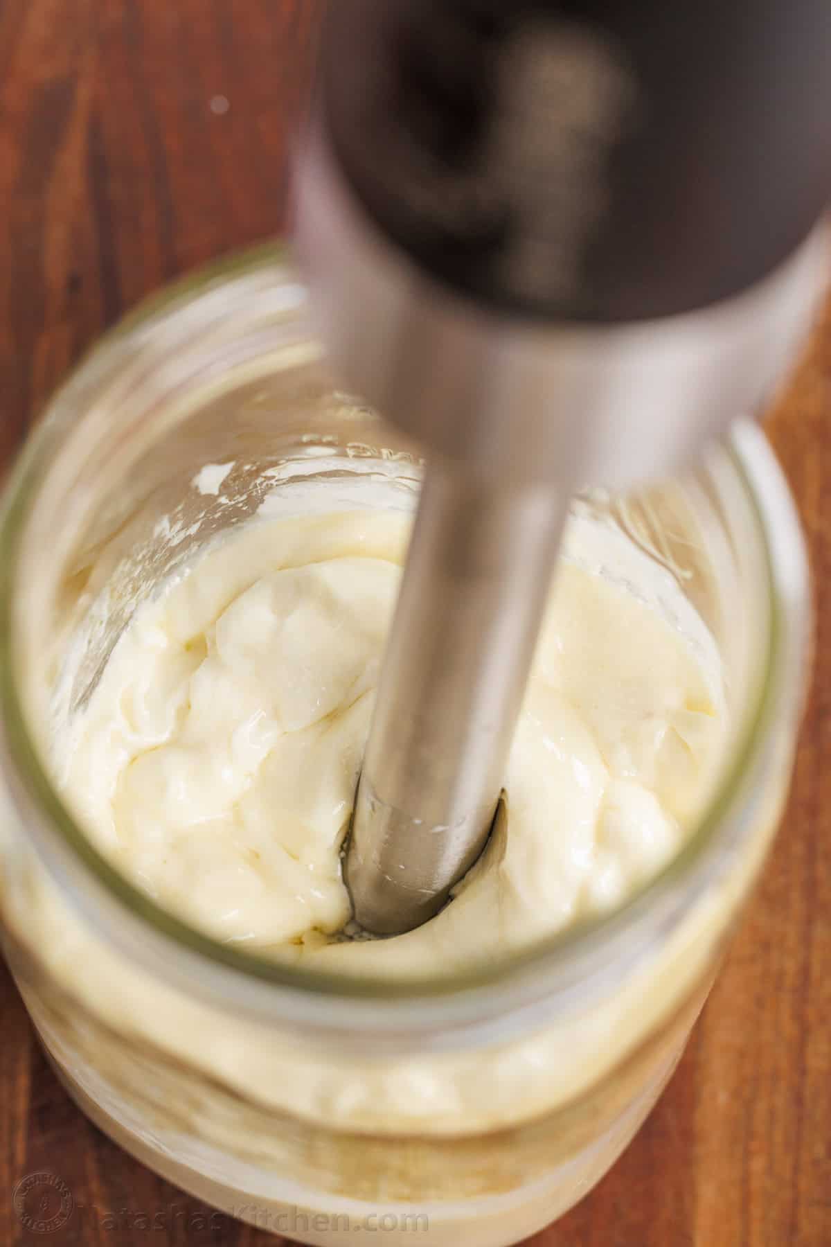 Replace store-bought mayo with your own creamy, delicious homemade mayonnaise—simple, fresh, and perfect for for everything from sandwiches to salads and more! An immersion blender in a glass jar emulsifying the ingredients for homemade mayonnaise