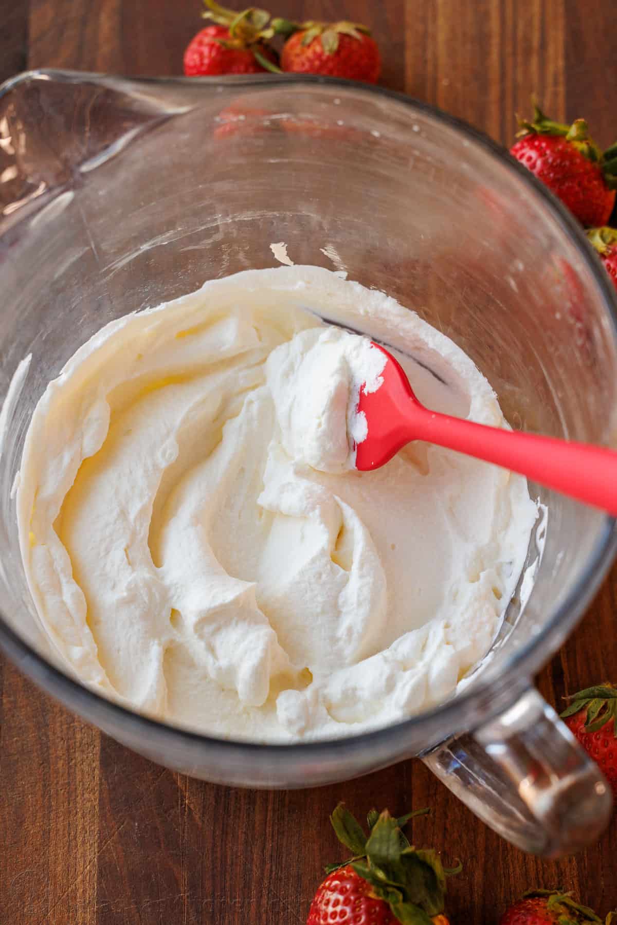 Make the Best Homemade Whipped Cream with 3 ingredients in minutes! Perfect for soft peaks or stiff peaks and to substitute storebought topping. Mixing bowl with homemade whipped cream on a wooden counter