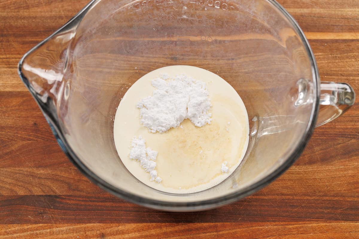 Make my Homemade Whipped Cream Recipe in less than 5 minutes with just 3 ingredients. Swap for Cool Whip for the best dessert dip or topping. glass mixing bowl with ingredients for homemade Cool Whip on a wooden counter