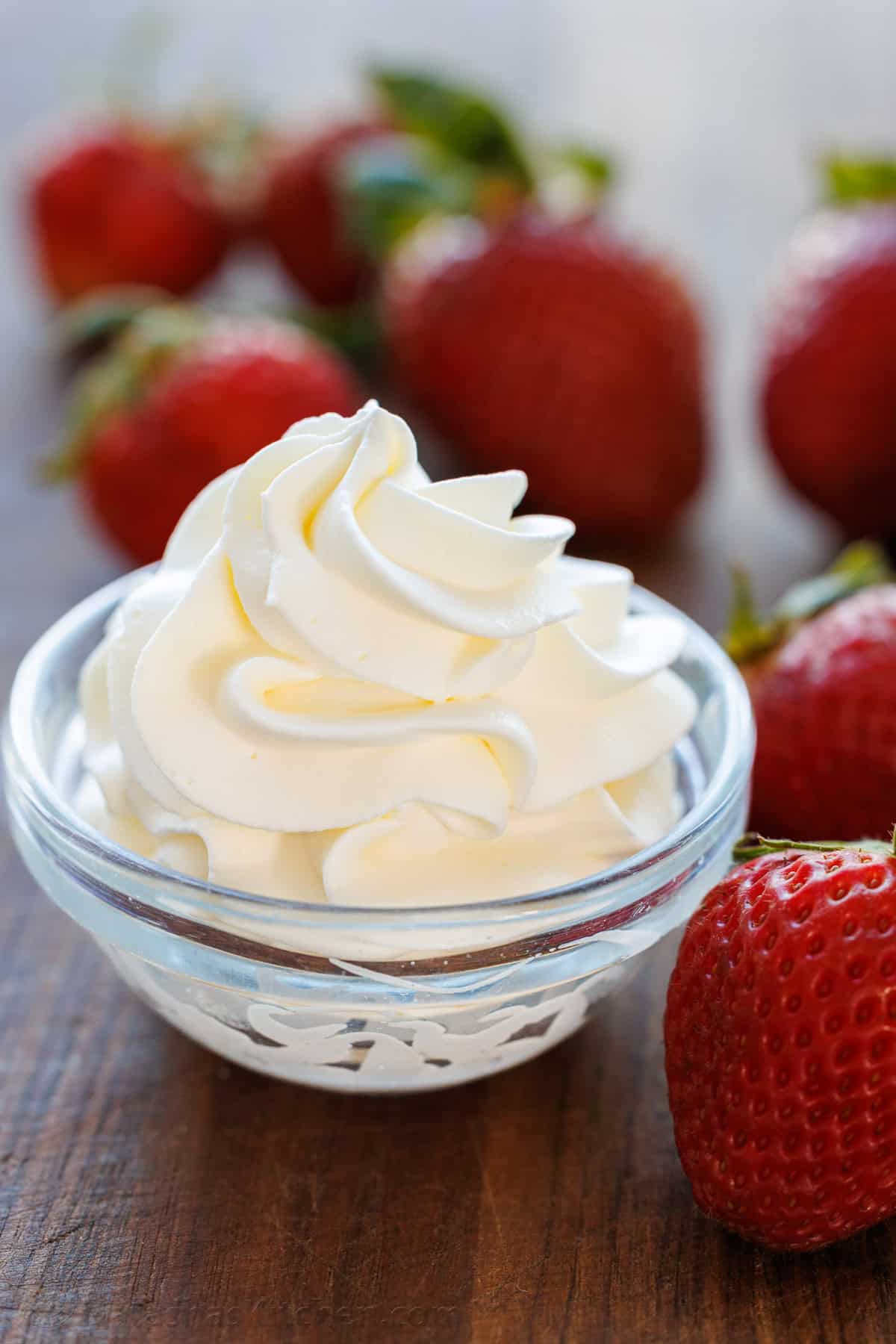 Make the Best Homemade Whipped Cream with 3 ingredients in minutes! Perfect for soft peaks or stiff peaks and to substitute store-bought topping. Homemade whipped dream piped into a small bowl with strawberries for dipping