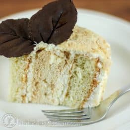 A piece of Kievsky cake on a white plate garnished with two chocolate leaves