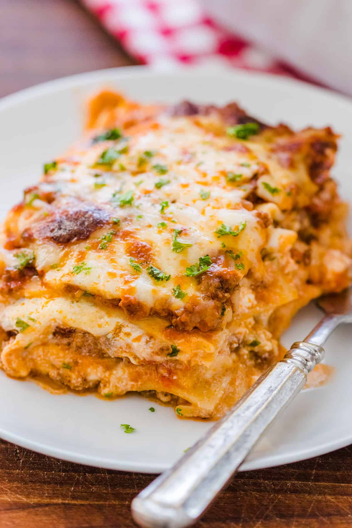 This easy Lasagna Recipe is meaty, cheesy, and flavorful. Perfect for a weeknight dinner or feeding a crowd, readers agree it's the best! Lasagna on plate with fork