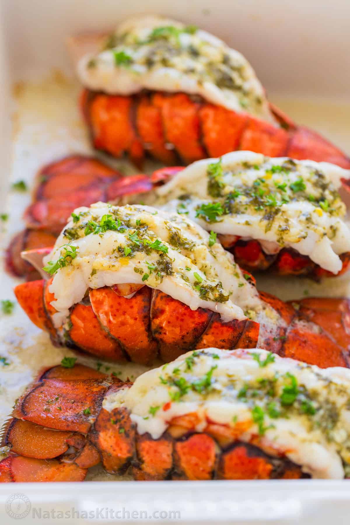 This Lobster Tail recipe with garlic butter sauce is juicy, flavorful, and easy. Includes an easy tutorial on how to butterfly lobster tail. Broiled lobster tail with lemon garlic butter in a serving dish