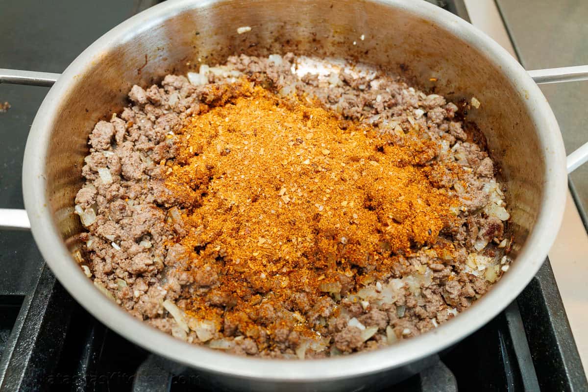 Ground beef in a skillet with taco seasoning on top