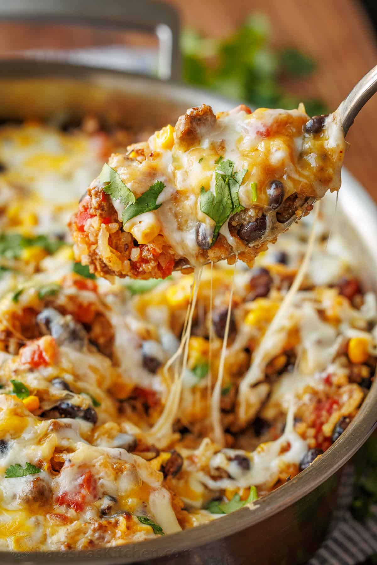 A serving spoon loaded with Mexican Ground Beef and Rice Skillet, showcasing the Mexican cheese pulls.