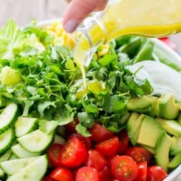 A bowl of Mexican salad with a lime dressing being poured over the salad