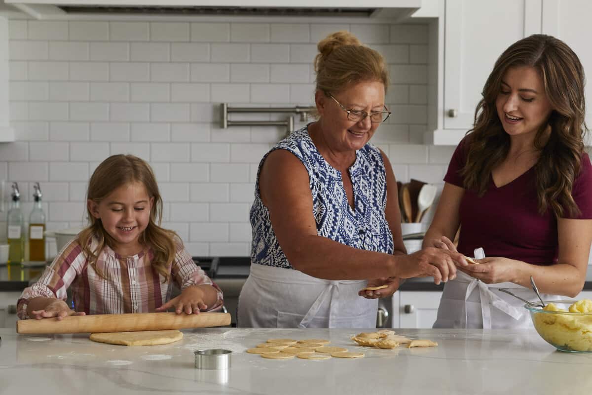 Pierogi filled with cheesy potatoes and served with crisp bacon, melted butter and sour cream. Homemade Pierogi is the ultimate comfort food! Grandma, Mom and daughter making pierogi together