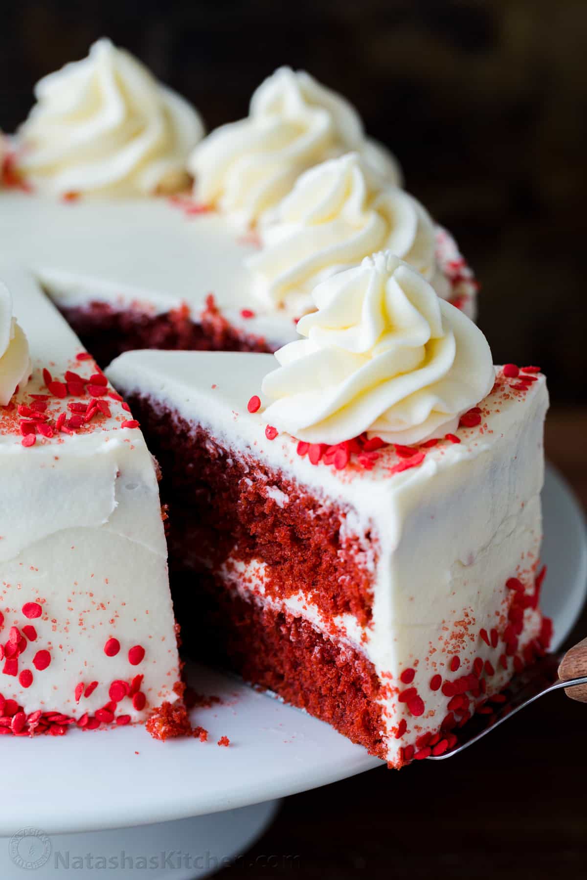 Our homemade Red Velvet Cake has a soft and moist crumb with the best Cream Cheese Frosting. Perfect for Valentine's, birthdays, or any special occasion. Red Velvet Cake slice pulled out of the cake