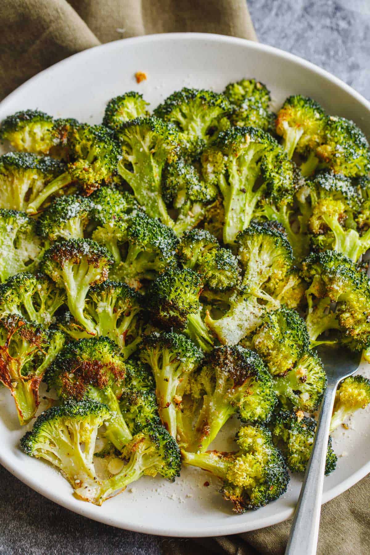 Oven roasted broccoli florets on a plate with serving fork