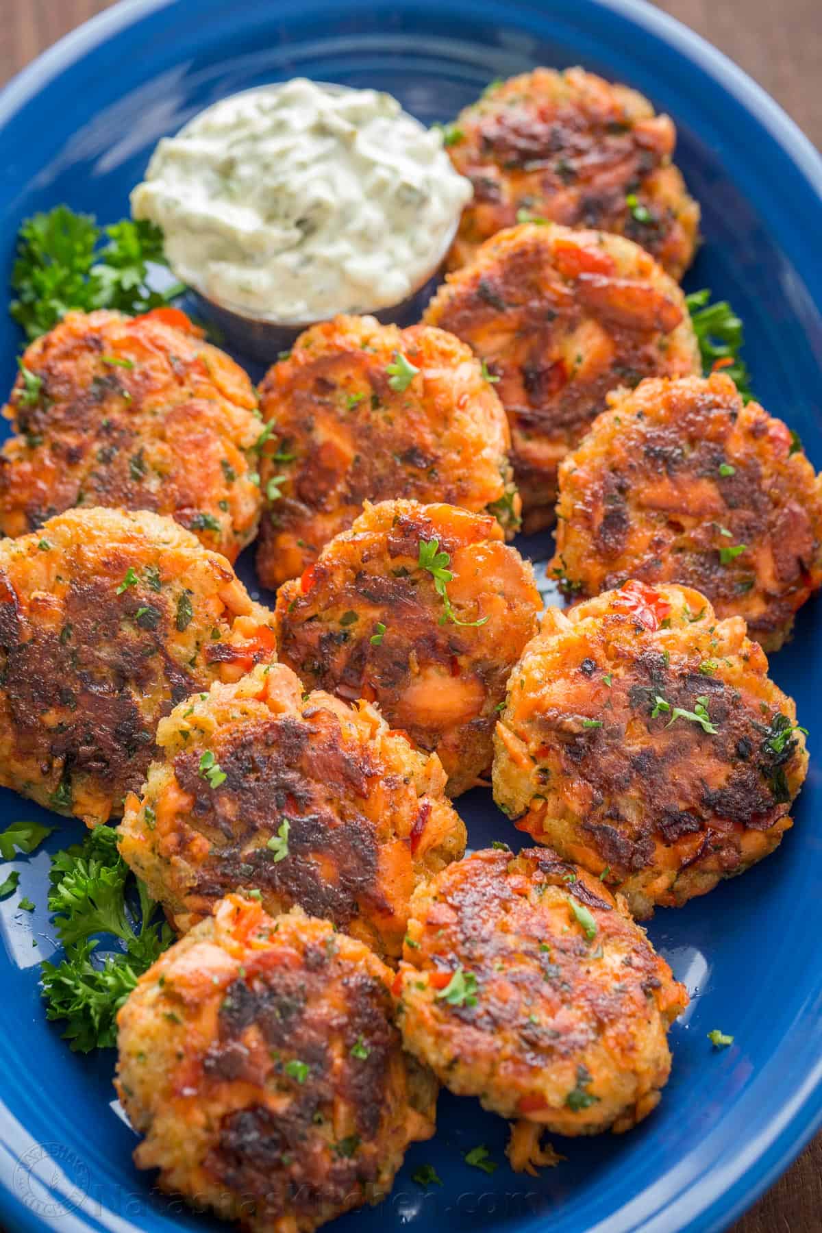 These salmon patties are flaky, tender, and flavorful with crisp edges and big bites of flaked salmon. Easy salmon patties are quick to make! fish patties on a blue platter with dipping sauce and parsley