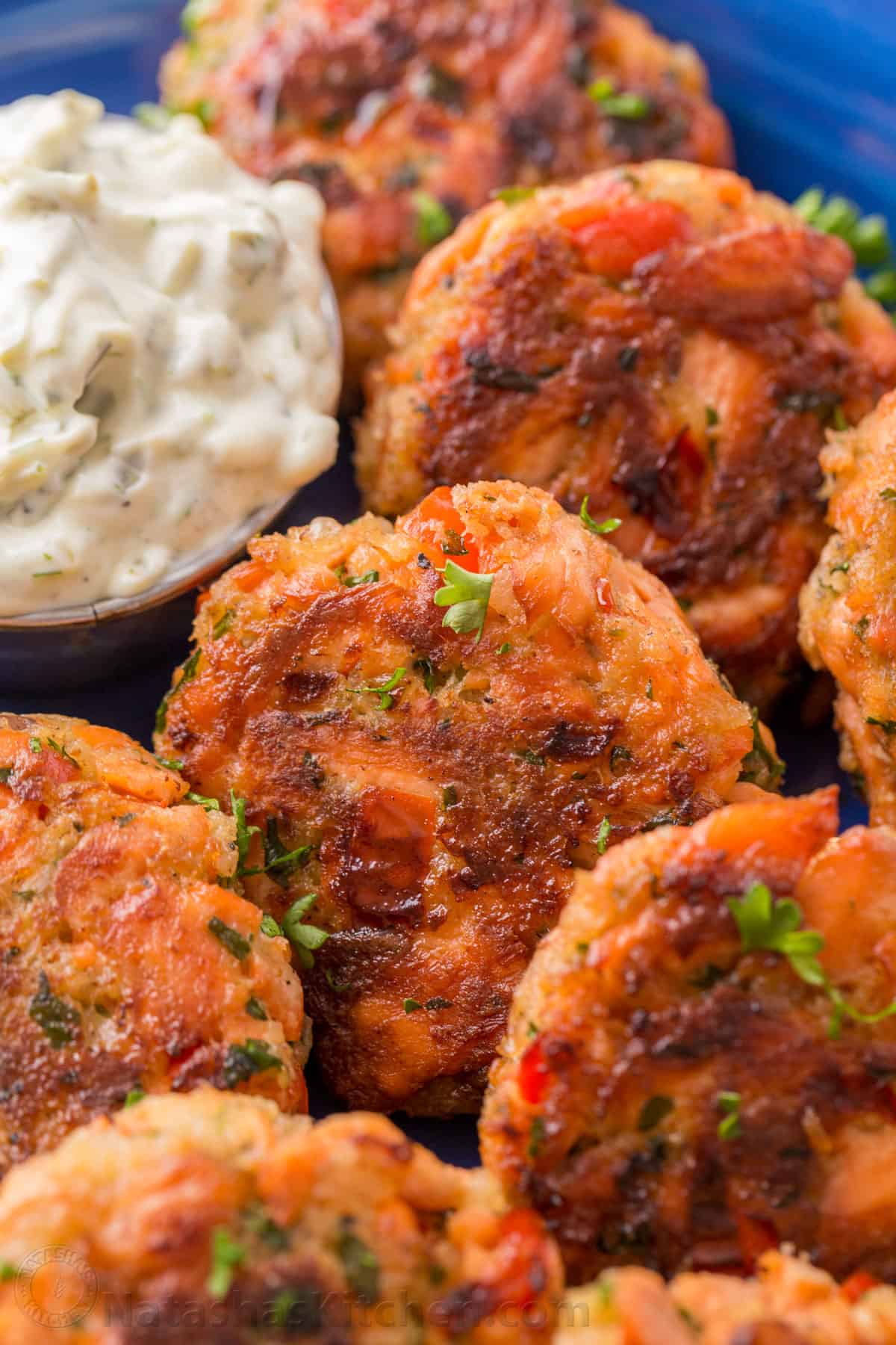 These salmon patties are flaky, tender, and flavorful with crisp edges and big bites of flaked salmon. Easy salmon patties are quick to make! close up picture of salmon patties on a blue plate with tartar sauce for dipping