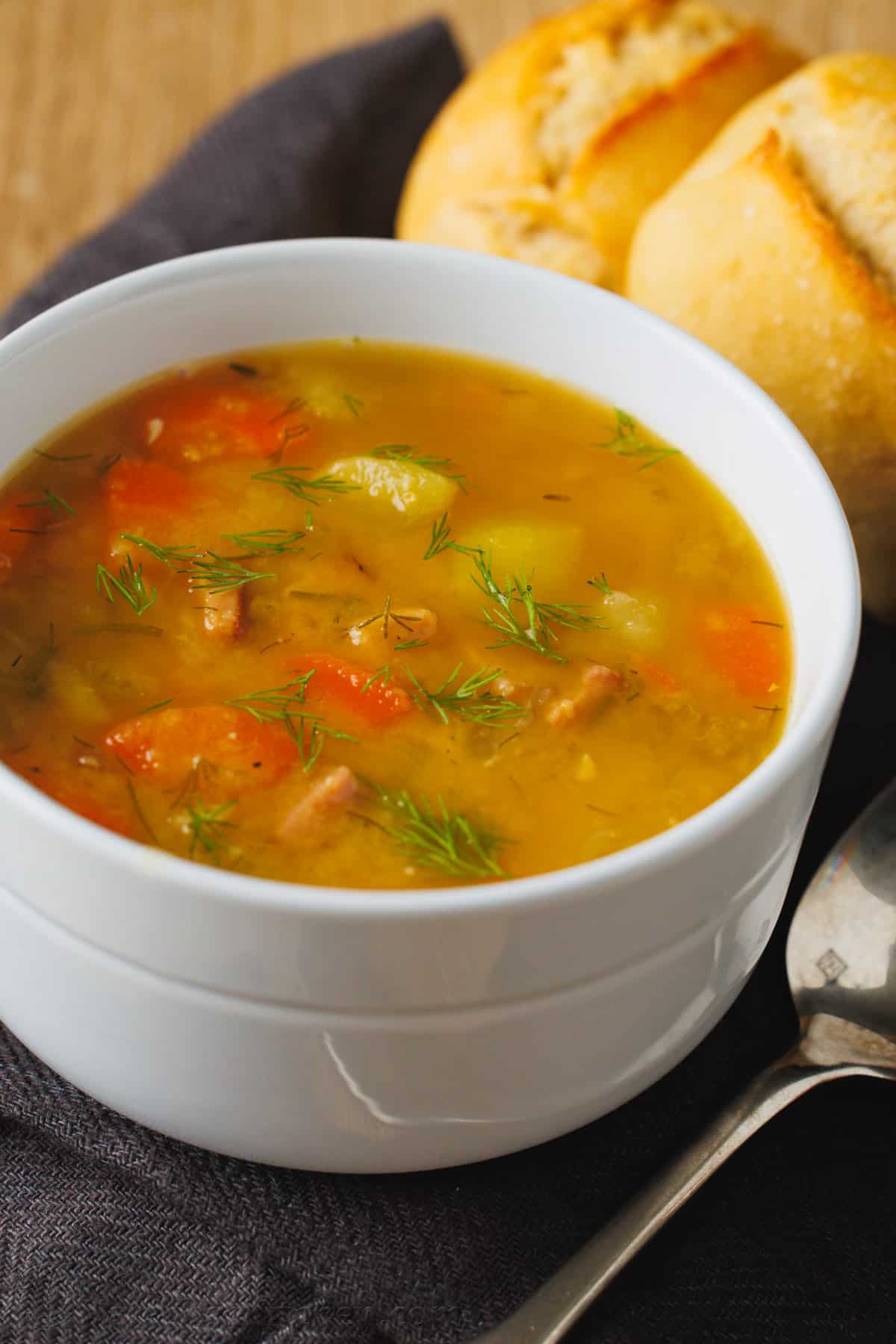 This Split Pea Soup is a nutritious blend of sweet golden peas and savory ham creating a rich and flavorful soup that's perfect for a cold winter day. Split pea soup in a bowl with bread on the side