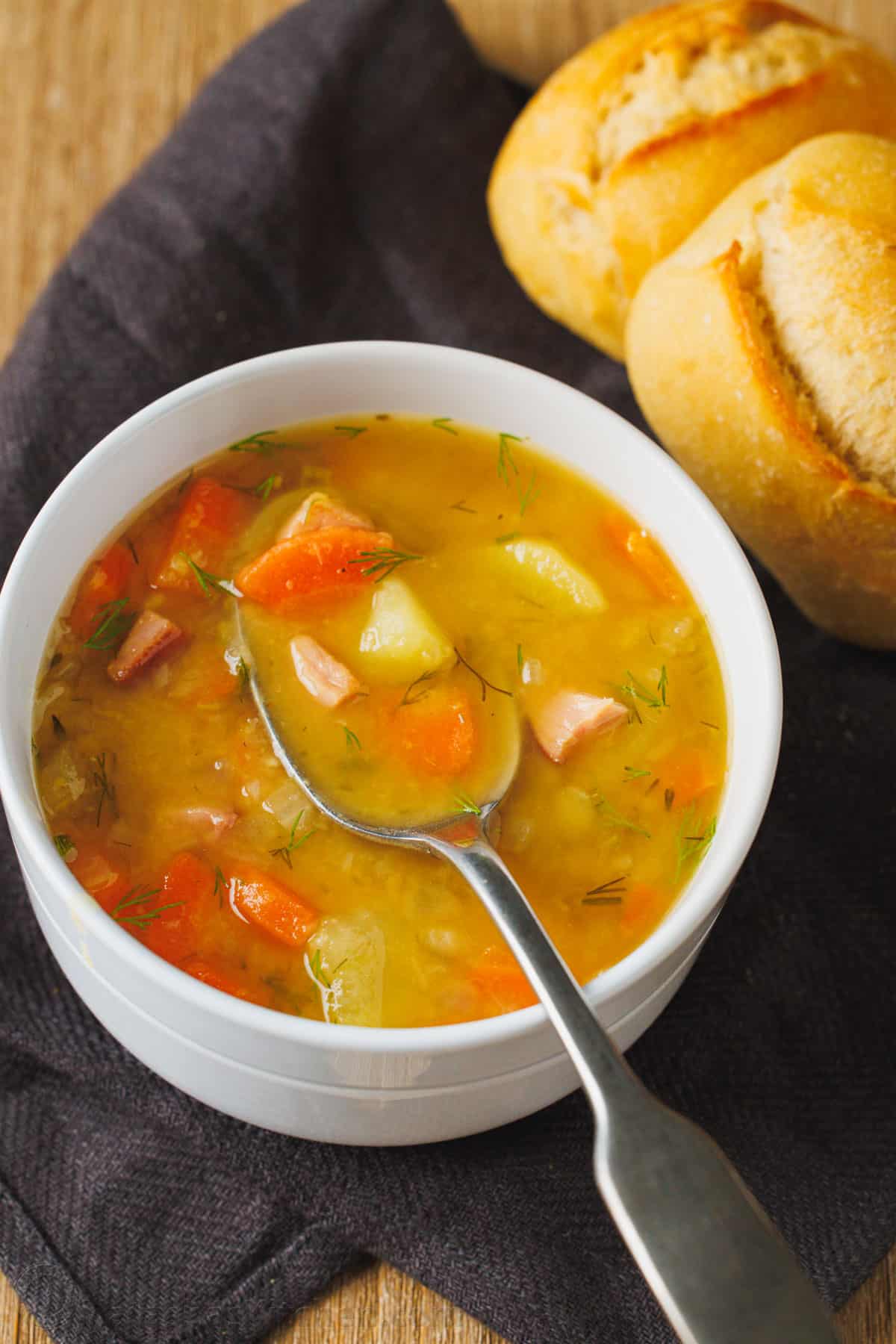 This Split Pea Soup is a nutritious blend of sweet golden peas and savory ham creating a rich and flavorful soup that's perfect for a cold winter day. Split pea soup in a bowl with a spoon showing the hearty vegetables in the golden broth