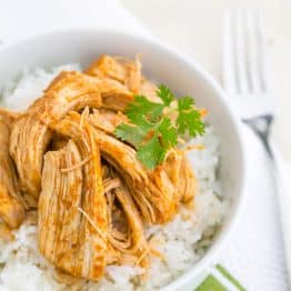 A bowl of rice topped with sweet and spicy baked chicken and garnished with parsley