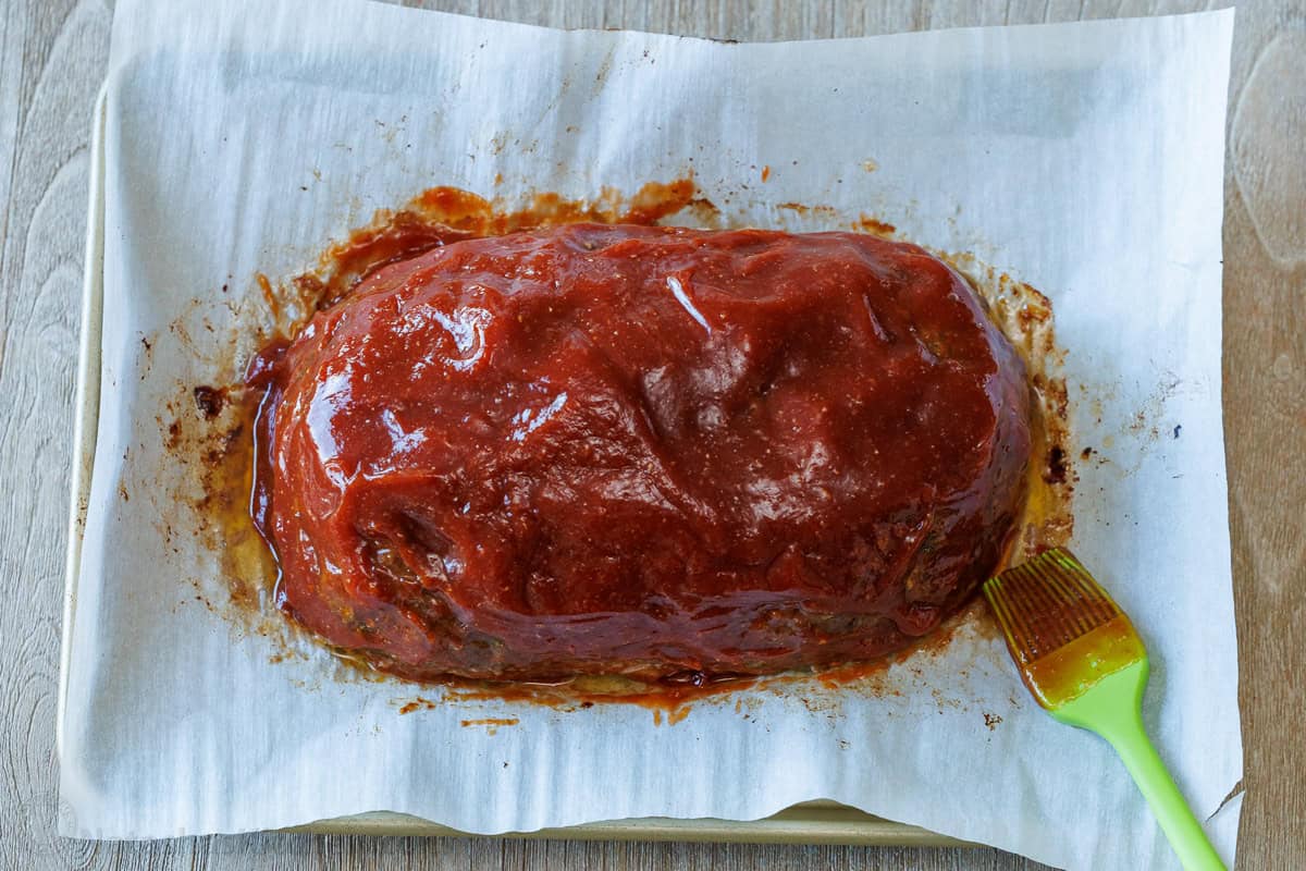 Simple Meatloaf recipe. Classic meatloaf recipe smothered with a sweet and tangy caramalized glaze. Brushing Sauce over meatloaf