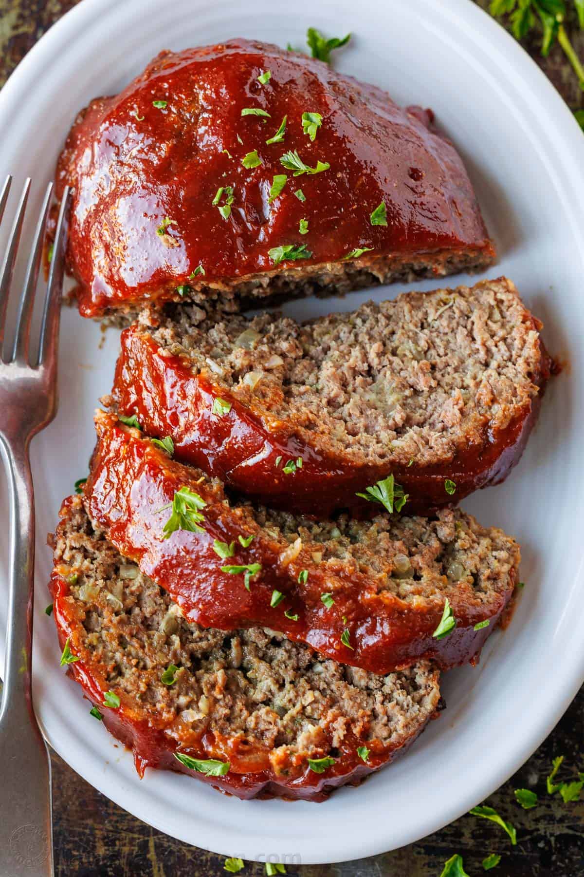 This is my favorite meatloaf recipe. The meatloaf is tender and juicy on the inside with a sweet and tangy glaze that adds so much flavor! The Best Meatloaf sliced and served on a white platter