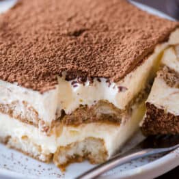 a piece of homemade tiramisu cake on a plate with a fork