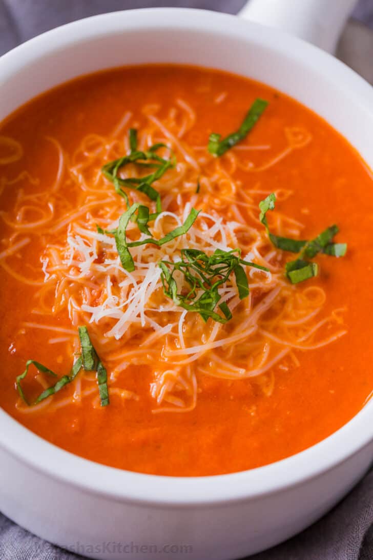 Homemade Creamy Tomato Soup is an easy 30-minute recipe. Tomato basil soup has a rich flavor profile and is balanced with cream and parmesan. Bowl of creamy tomato soup garnished with parmesan and basil