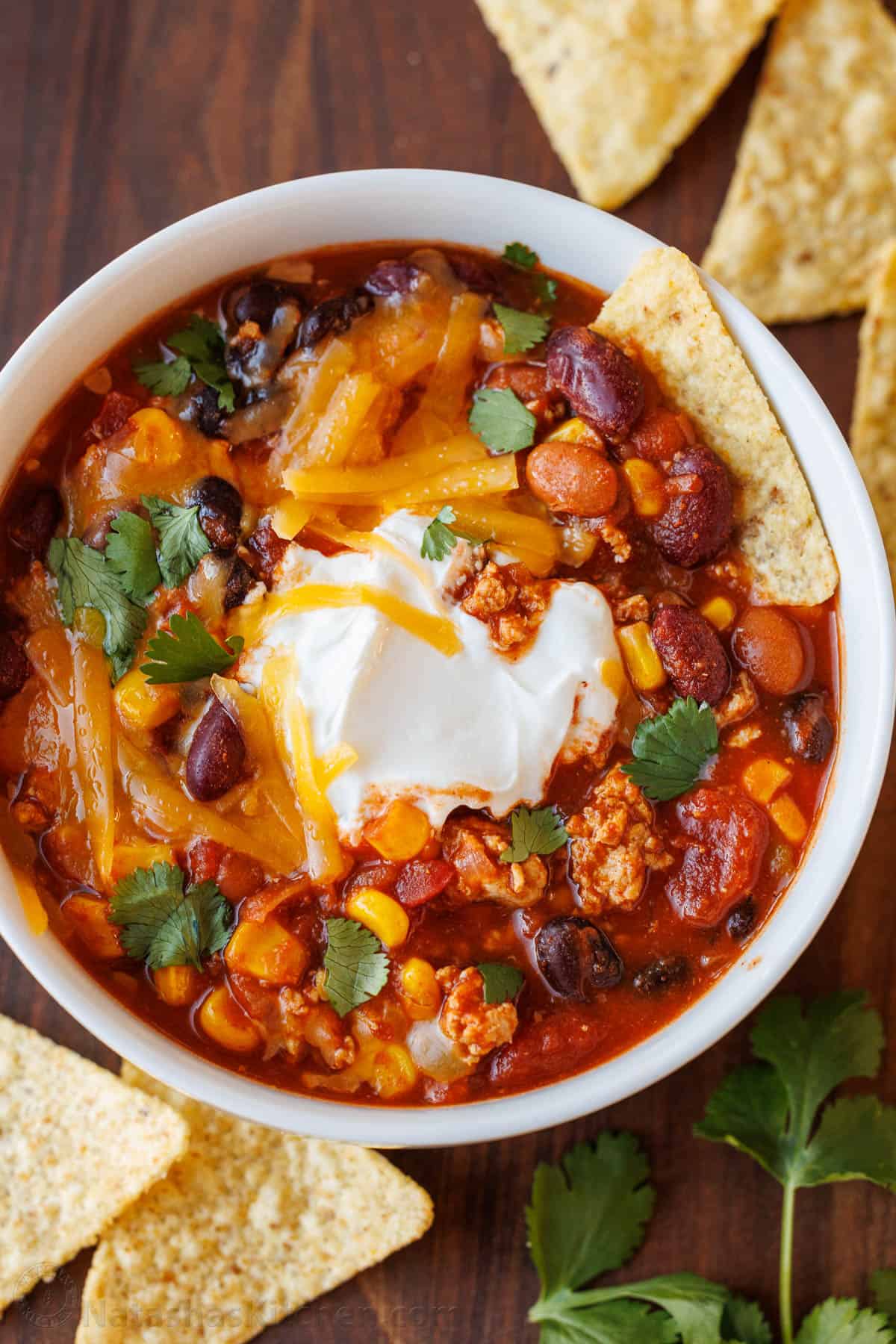 Bowl of turkey chili garnished with sour cream and chips
