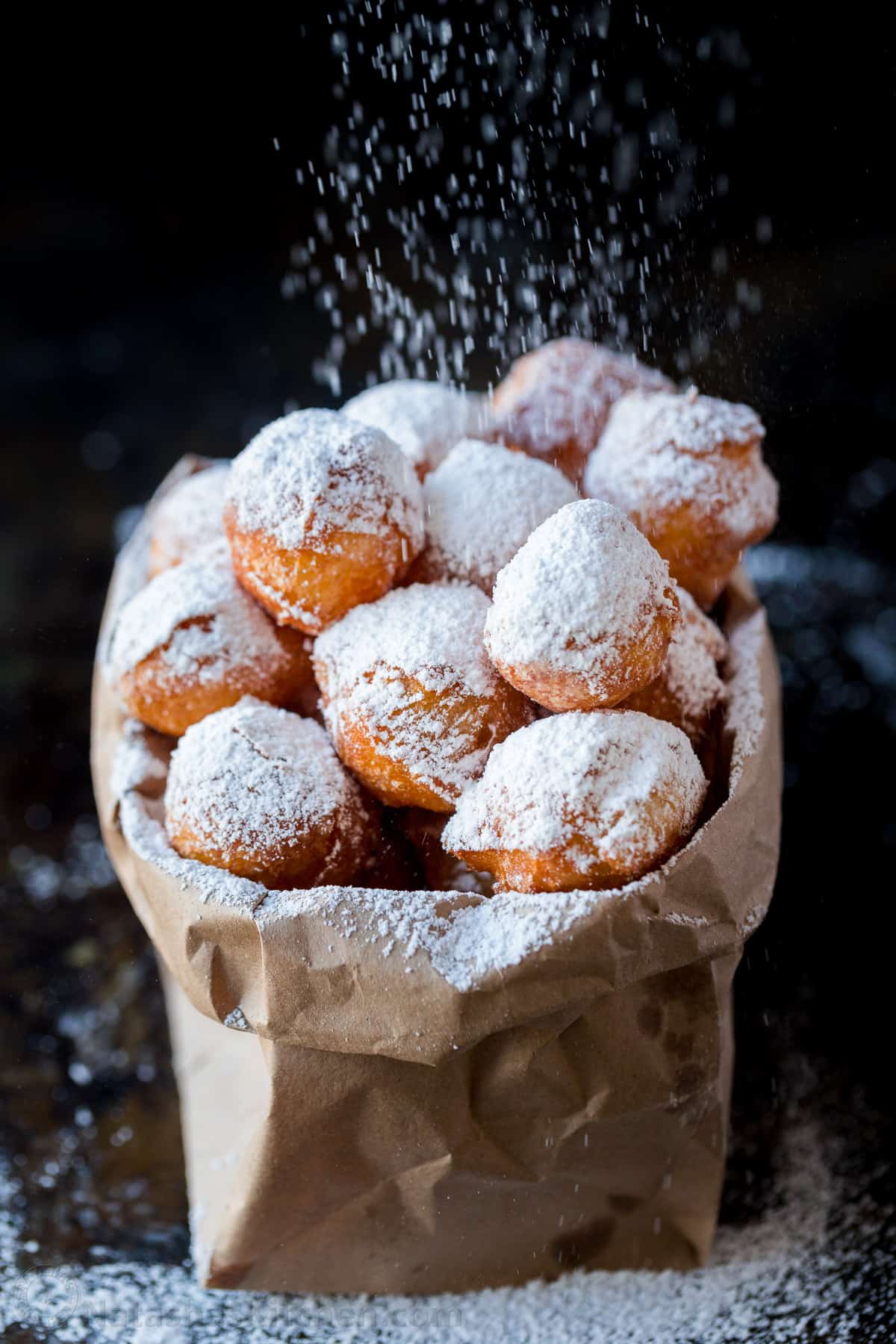 Zeppole donuts are rolled in sugar with a fluffy, melt-in-your-mouth center. These Italian donut holes are simple to make and always disappear fast. Zeppole in paper bag dusted with powdered sugar.