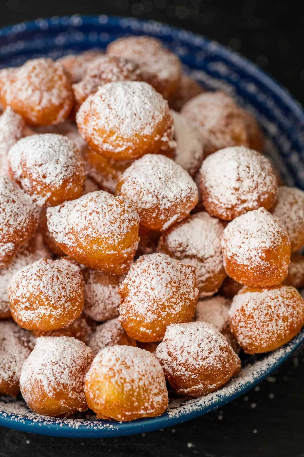 Zeppole donuts are rolled in sugar with a fluffy, melt-in-your-mouth center. These Italian donut holes are simple to make and always disappear fast. Zeppole in a bowl covered with powdered sugar